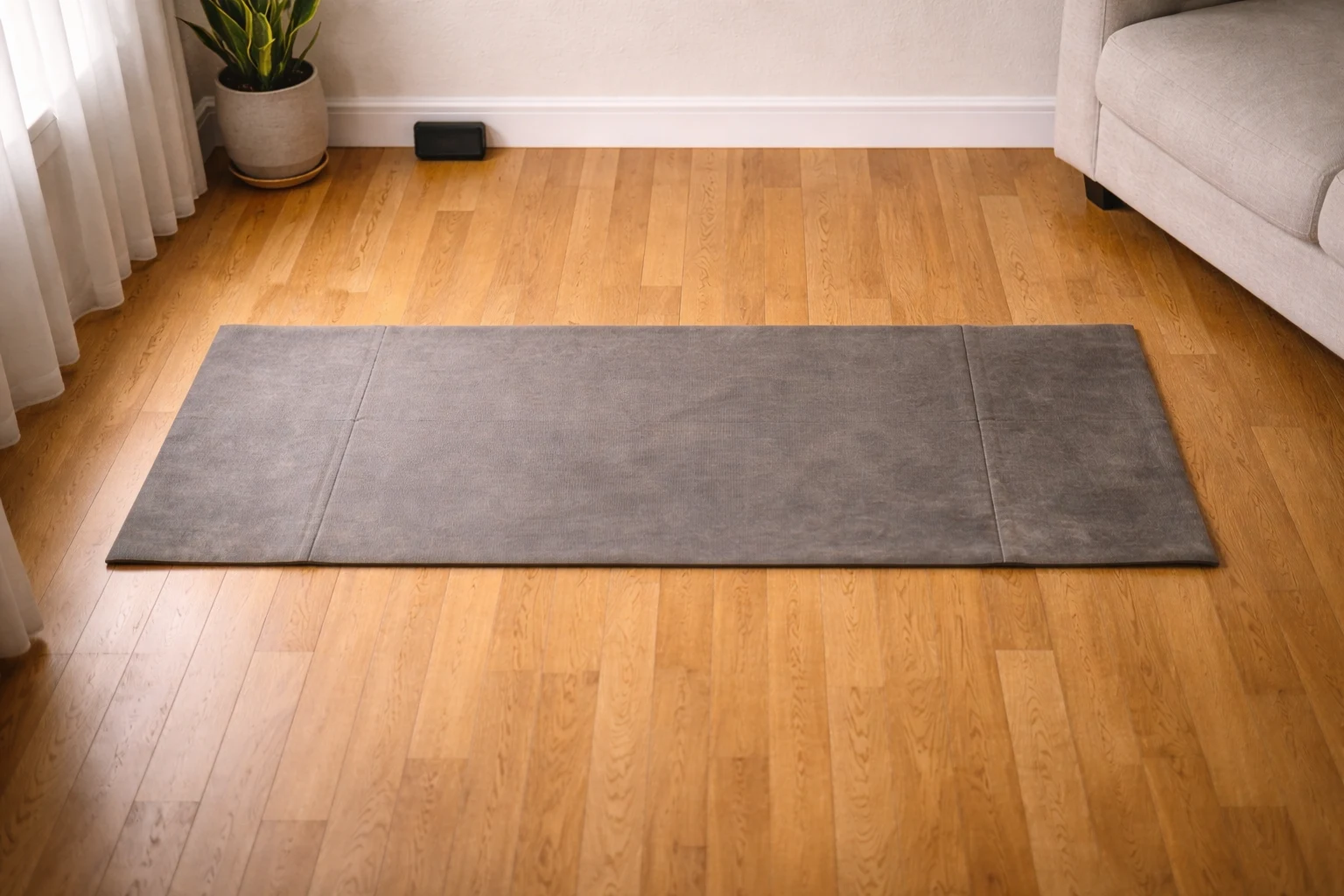 Overhead view of a yoga mat on a cleared apartment floor — showing the minimal space needed for a complete home workout